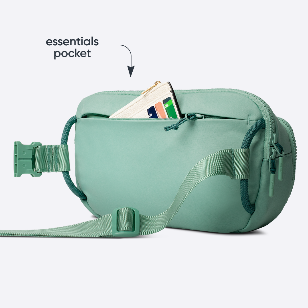 All-Day Crossbody in Sea Glass, sage mint belt bag with matching strap and front zip pocket holding a card, with text reading "essentials pocket" pointing to the open pocket