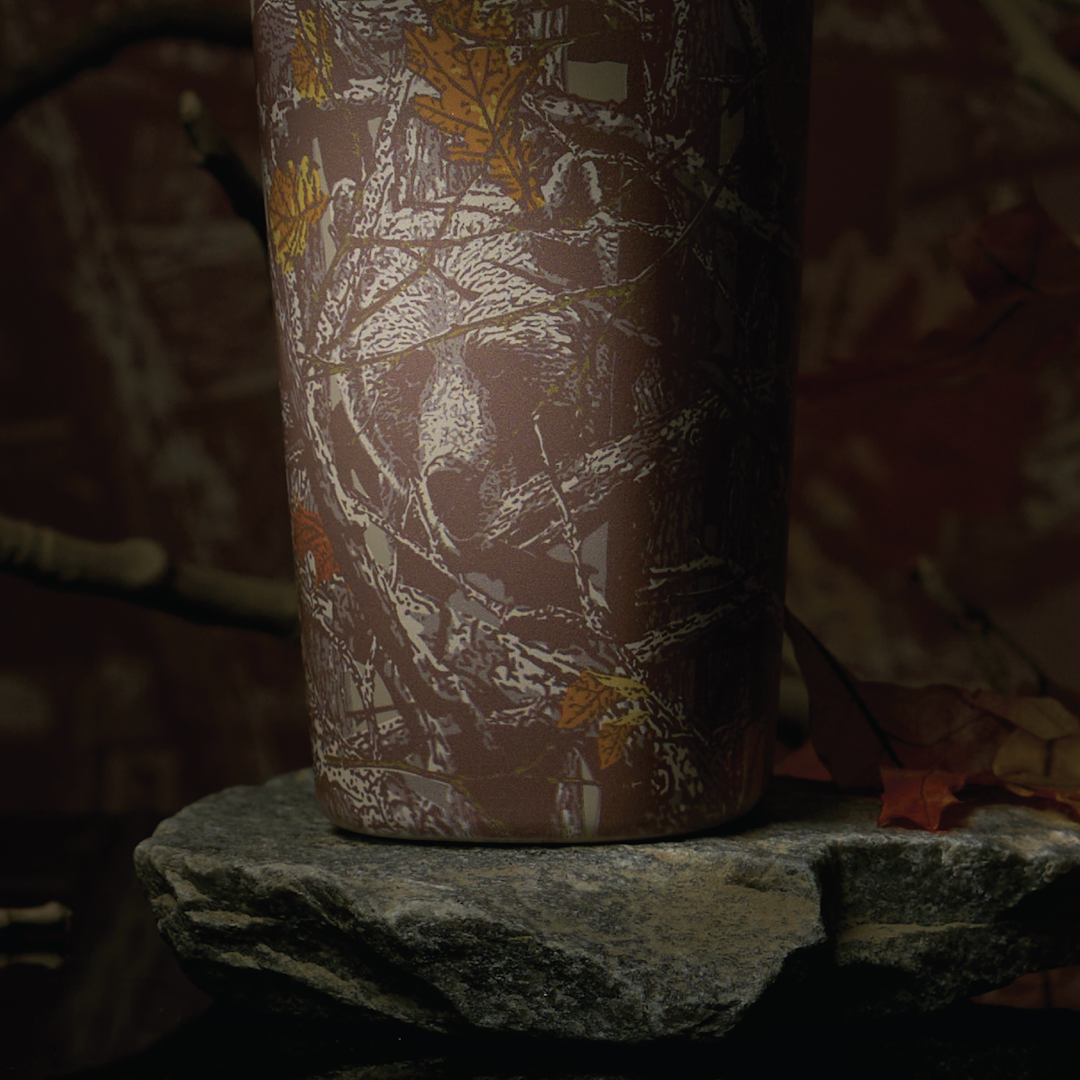 SmoothSip Slider in Out of Sight, back view of woodland camo patterned body shown on a rock in a forest setting