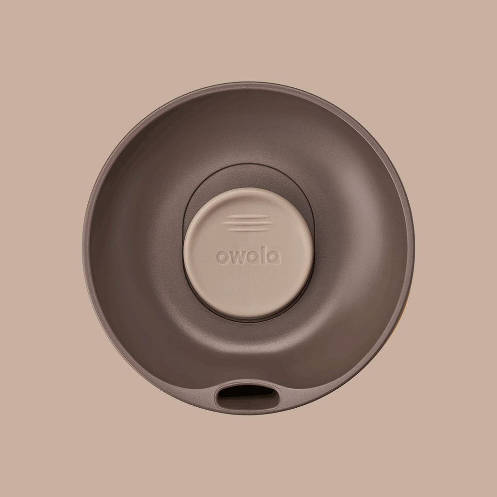SmoothSip Slider lid in Out of Sight, top-down rotating view of dark brown lid with beige slider button featuring embossed logo, sip hole visible at bottom edge